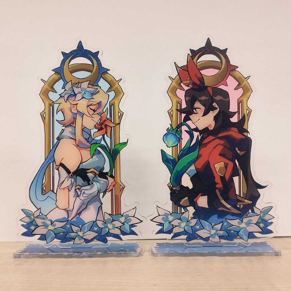 acrylic standee of Lumine and Amber from Genshin Impact facing each other, holding a Windwheel Aster and Small Lamp Grass respectively