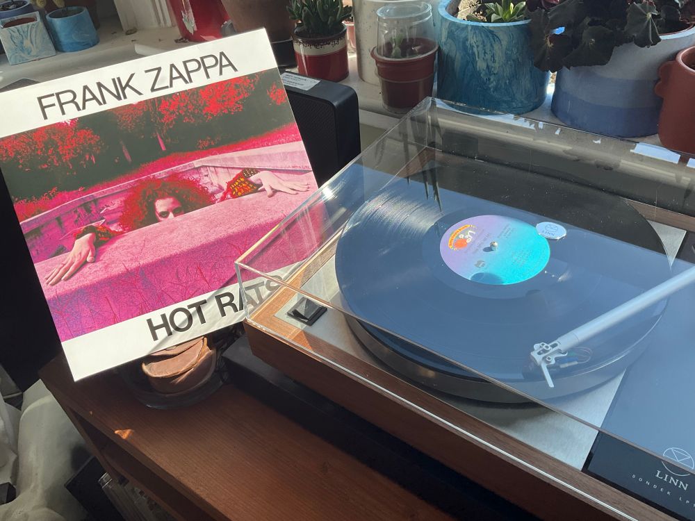 Front of Gatefold album cover visible of Hot Rats sitting to left of turntable playing the record