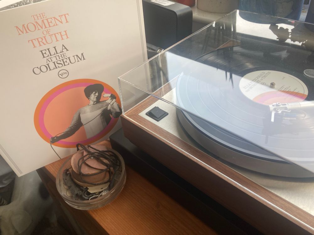 Ella Fitzgerald album on the left of photo leaning against a turntable which has the record playing.