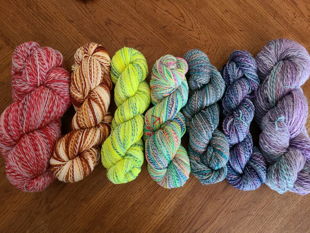 7 skeins of handspun yarn in rainbow order from red to purple 