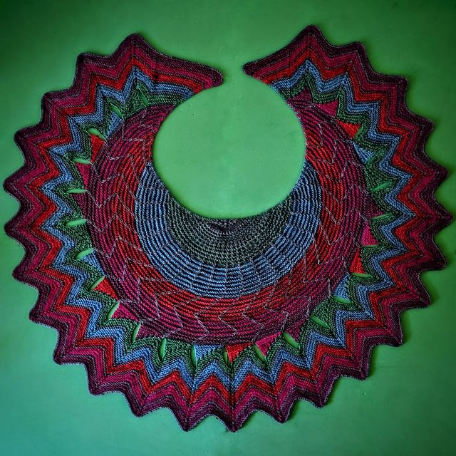 A jewel coloured shawl in green, blue, red and purple, with different textures. Layed down flat in circular shape on a green background.
Pattern: Shawl Party by Stephen West
Yarn: mominoki yarn Sock Happy