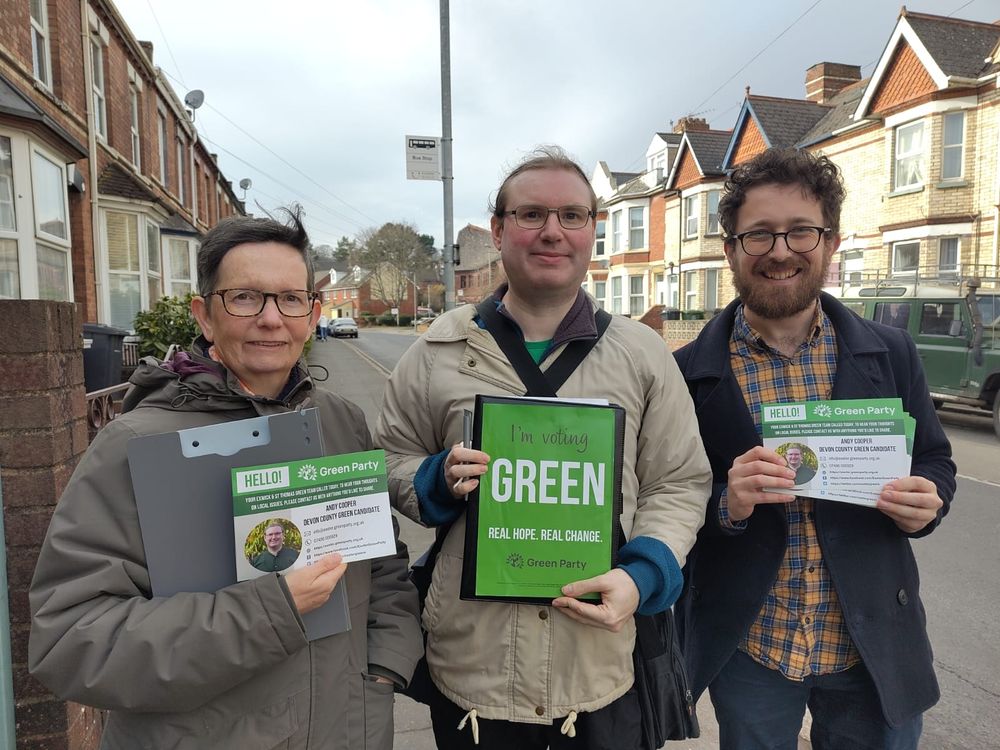Devon County Council candidate for Exwick & St Thomas, Andy Cooper (centre), with two volunteers in a street in St Thomas Exeter. Andy is holding a poster such reads: I'm voting Green.