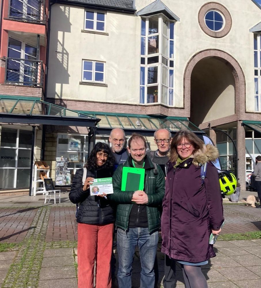 A picture of Councillors Diana Moore and James Banyard, Green Party councillors in St David's ward, with three volunteers smiling in the sunshine by Exeter Quay.