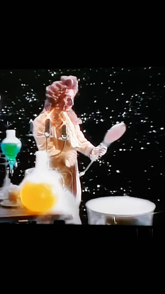 A weird lil monster floating in the universe next to potions and vats and stuff