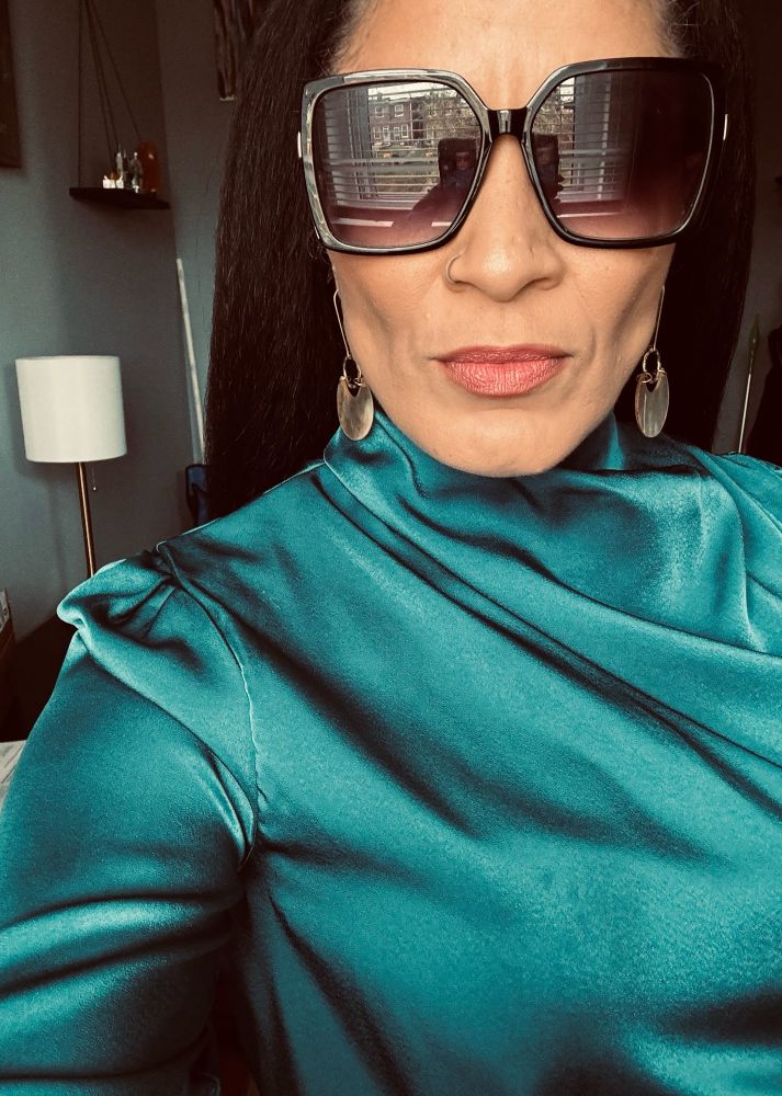 Lady in dress and sunglasses taking selfie. 