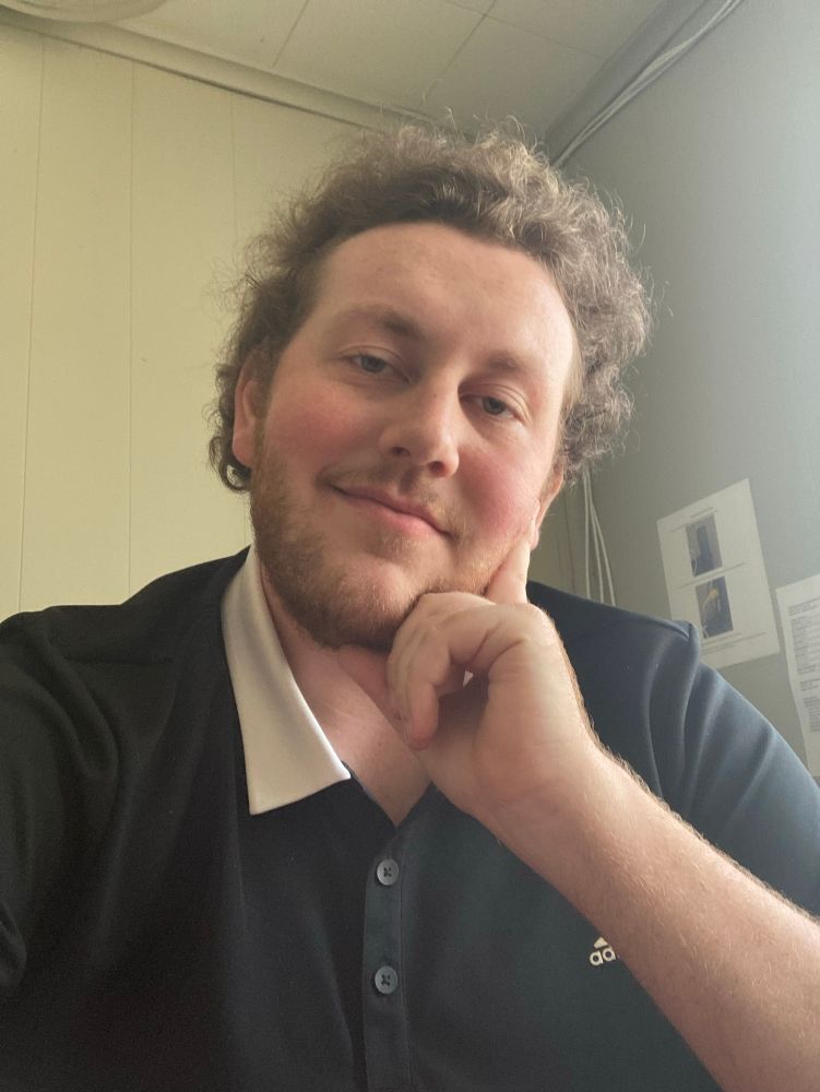 me in a black polo with a white collar. I have shorter hair and my hand is up against my face