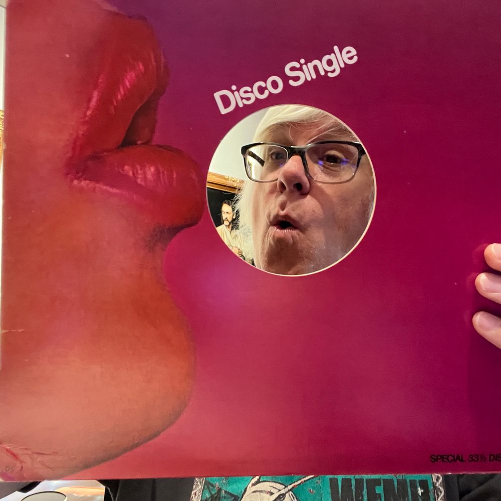 Me looking through the center of a company 12” sleeve with a woman puckering up 