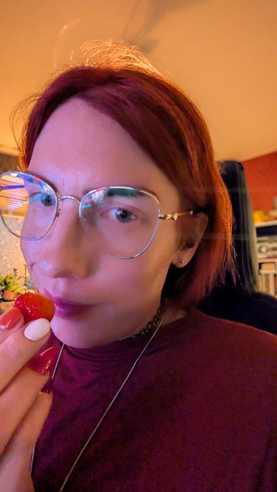 A selfie of me eating a strawberry and looking coy