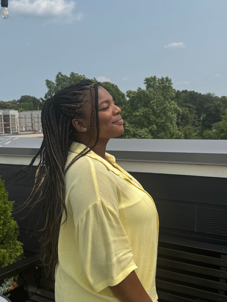 A woman wearing a yellow two piece set with her eyes closed and smiling at a rooftop bar on her birthday.