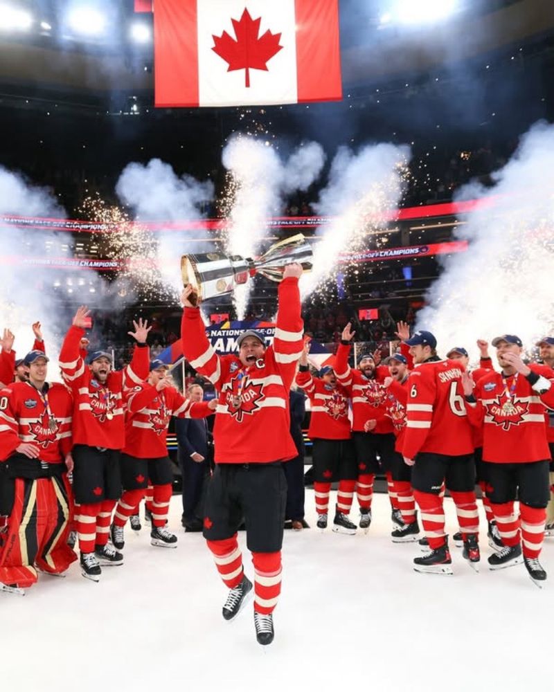 Sidney Crosby of the Pittsburgh Penguins, raising the winners trophy for the Four Nations tournament where he was team captain of Canada. The rest of team Canada is surrounding Crosby with joyful excitement backed by smoke cannons and fireworks.