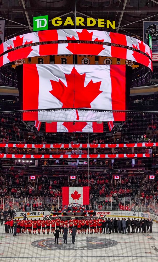 The Canadian flag rises as the Canadian National Anthem is played after Team Canada won against the US in the Four Nations tournament. Team Canada won the tournament and remains the world champions of hockey. There are digital signage projecting the Canadian flag throughout the arena as well.