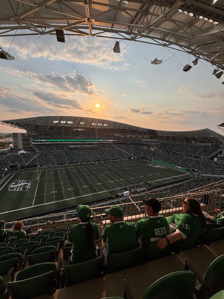Photo shows a football stadium from the top seats as the sun sets. 