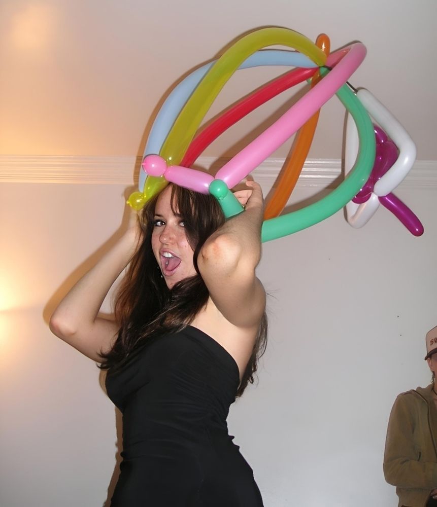 Young Cooper streaming in a black dress holding onto any enormous crown made of balloons on top of her head