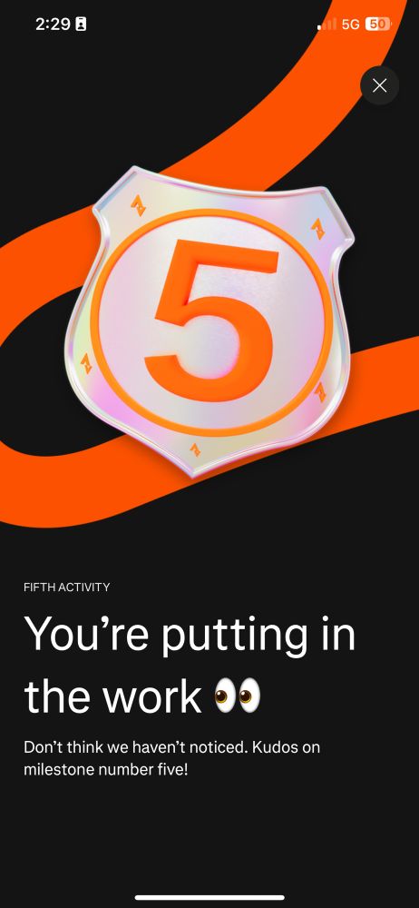 A silver shield decorated with orange Strava logos and the number 5. Text below it reads
"FIFTH ACTIVITY
You're putting in the work 👀
Don't think we haven't noticed. Kudos on kilestone number five!"