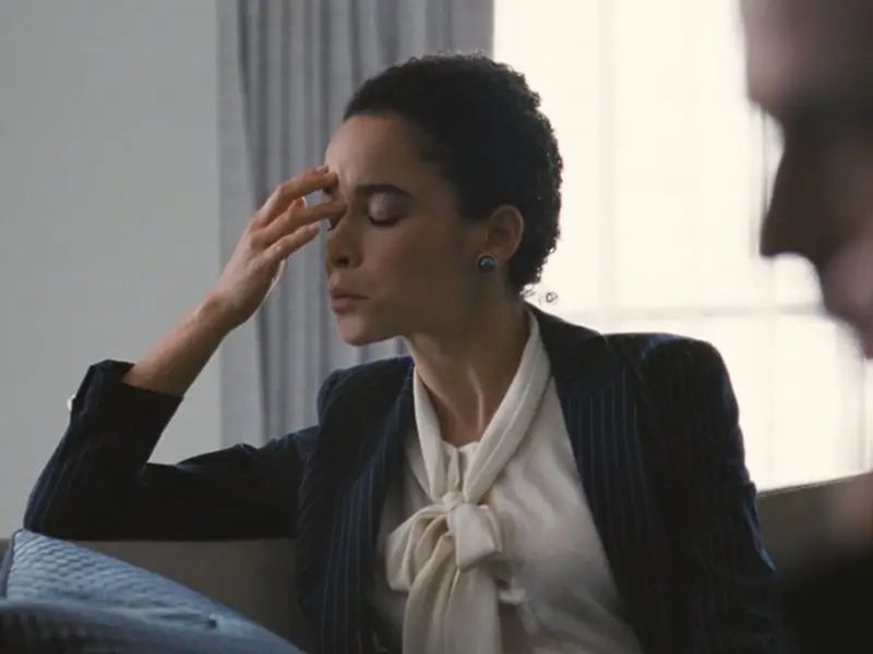 Jess from Severance looking exasperated, resting fingertips against her forehead with eyes closed