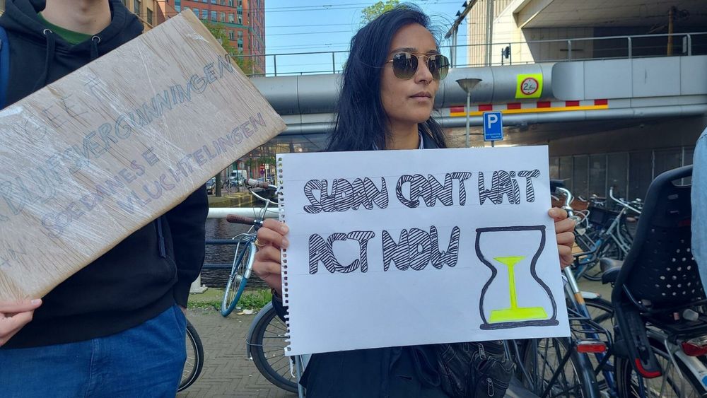 Activiste met actie-sign:

"Sudan cant wait
act now"