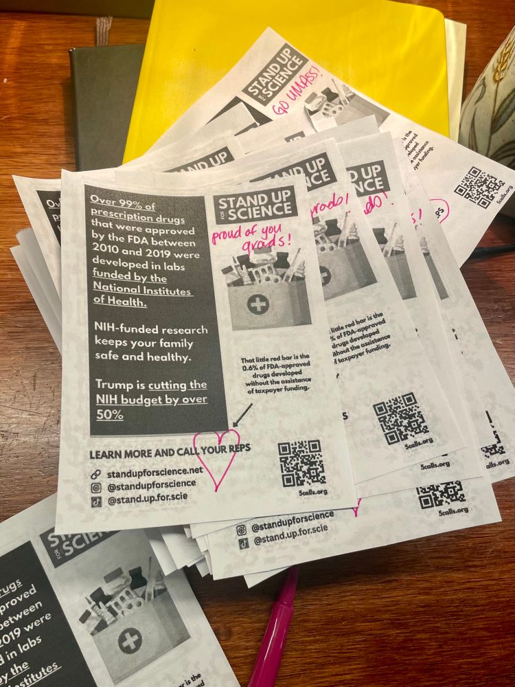 À pile of micro flyers printed out, with “go UMass” and “proud of you grads!” written on them, and a heart around the phrase “call your reps”