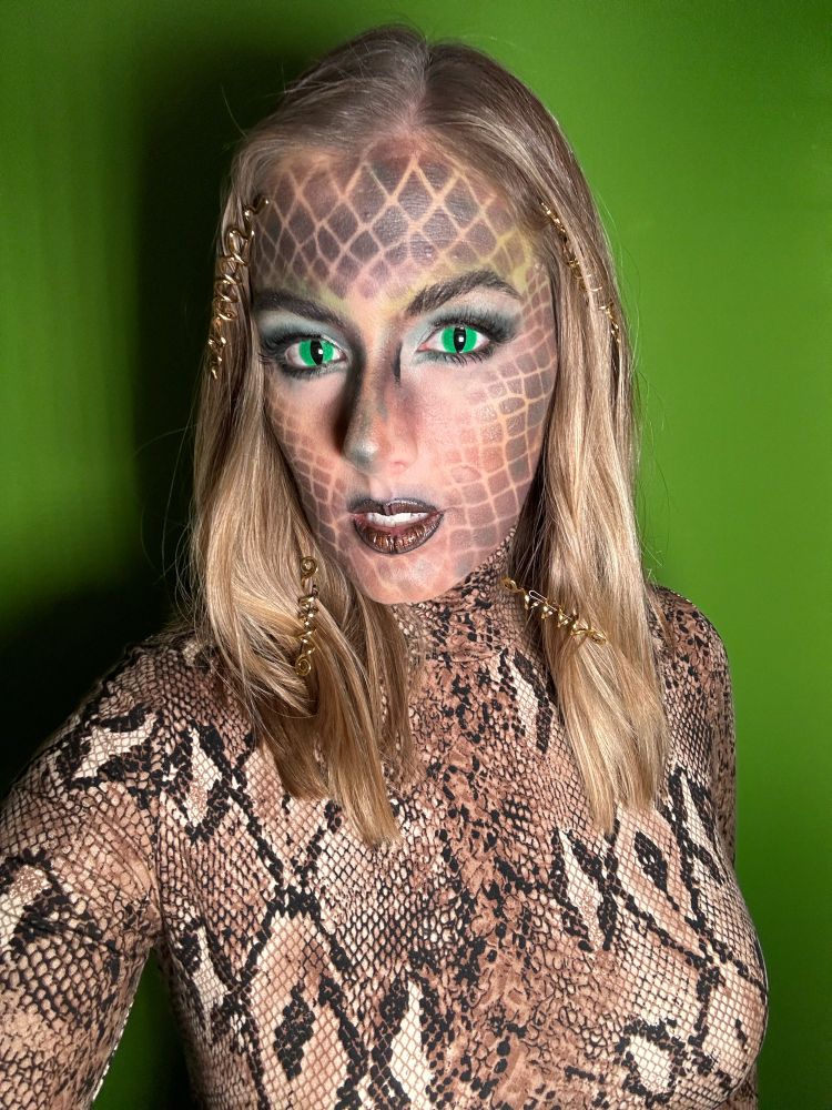 Snake makeup or Medusa makeup. Green snake contacts for the eyes, snake skin makeup on the face and a snake skin long sleeve shirt.