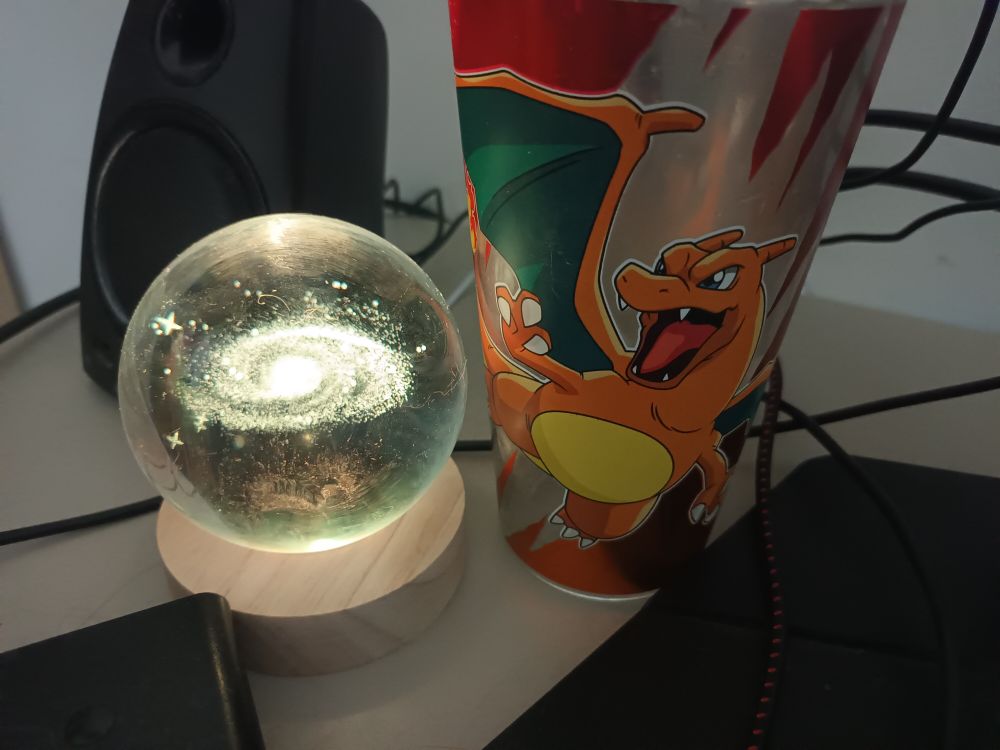 The same charizard glass, now next to a glass ball with a galaxy shape inside
