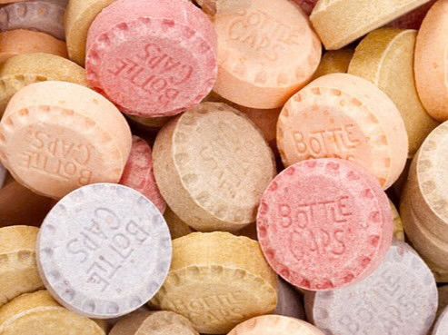 A pile of candy discs in muted purple, red, brown, and beige