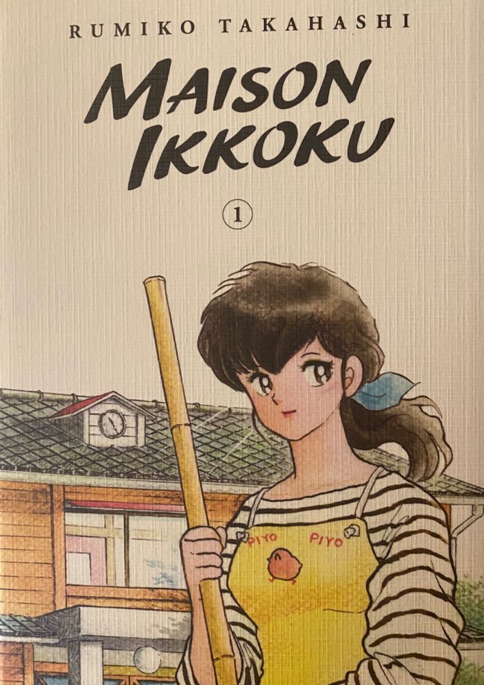 Maison Ikkoku volume 1 cover - a woman stands in the foreground wearing a striped shirt and a yellow apron that says “piyo piyo” on it. A large boarding house stands in the background. 