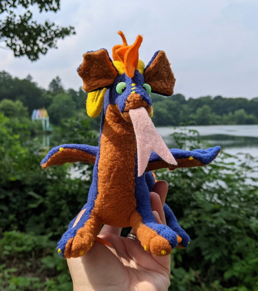 a dark blue dragon plushie with an orangy brown underbelly and yellow horns/claws, and aqua eyes