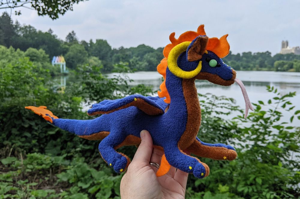 a dark blue dragon plushie with an orangy brown underbelly and yellow horns/claws, and aqua eyes