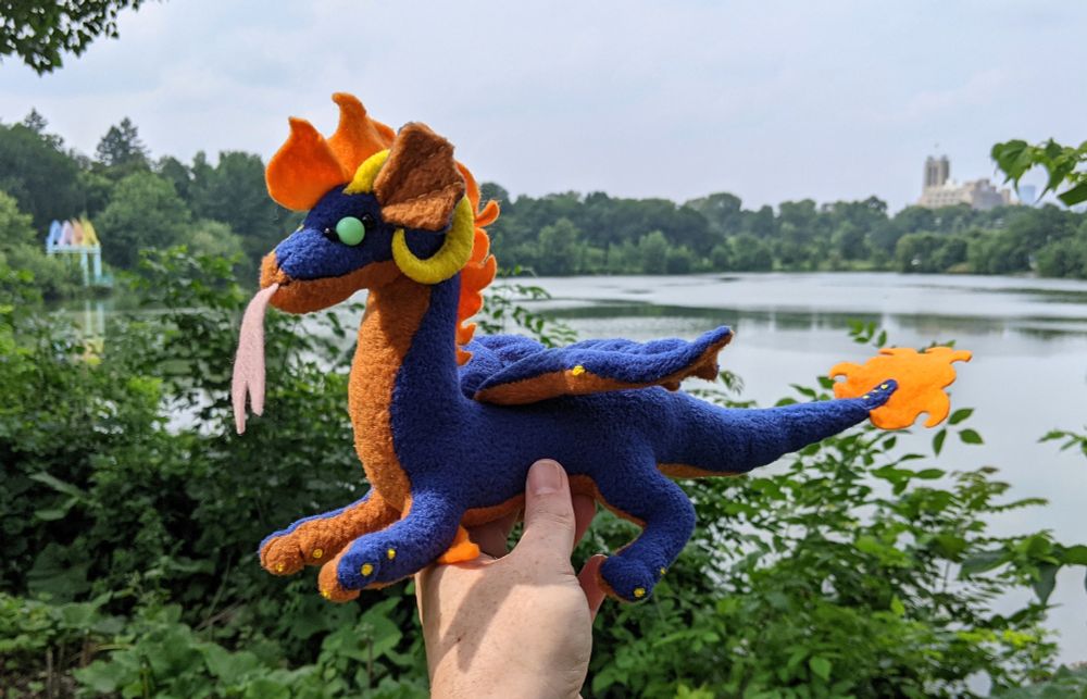 a dark blue dragon plushie with an orangy brown underbelly and yellow horns/claws, and aqua eyes
