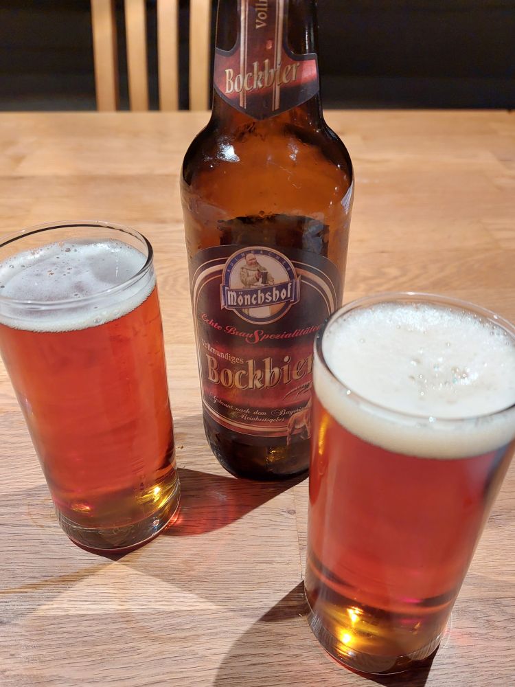 Zwei Wassergläser mit Bier auf einem Tisch, dazwischen eine Flasche Mönchshof Bockbier