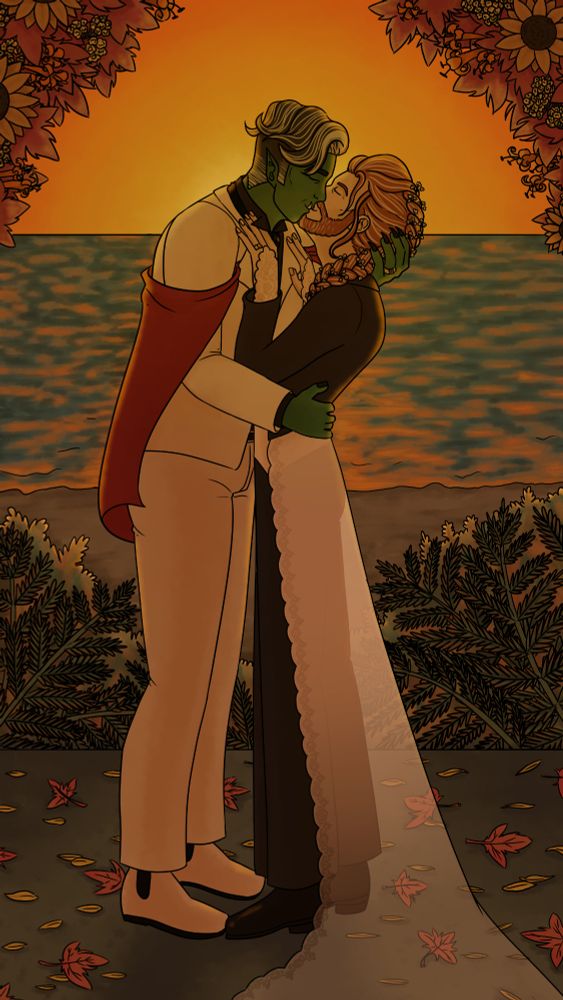 Fjord and Caleb kissing in wedding suits. They are under an arch of fall foliage in front of the sunsetting on the sea.