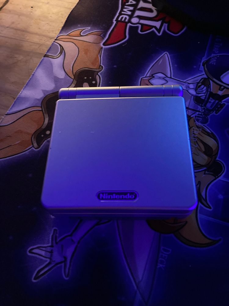 A Nintendo Gameboy Advance SP Silver Edition  closed on a desk