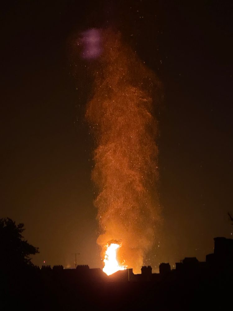 A plume of embers above a bonfire taken from a distance 