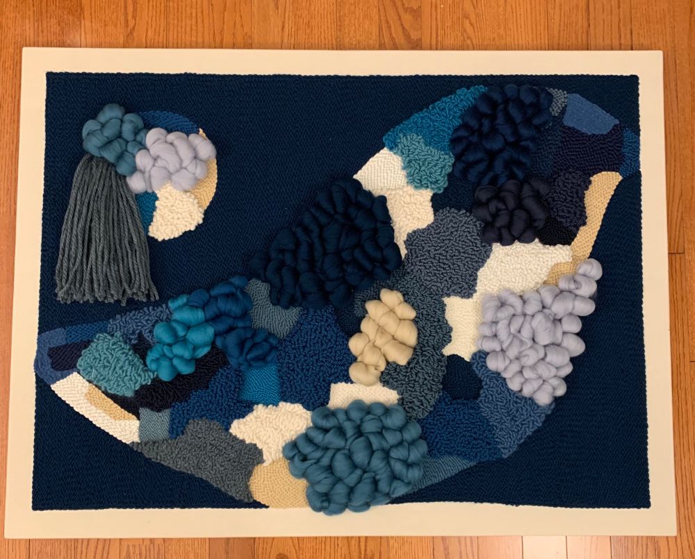 A abstract punch needle piece that is punched on monks cloth with blue, cream, and white yarn, as well as roving to add more texture. This piece uses varying loop heights creating a landscape that features both flat stitches and differentiating loop lengths.