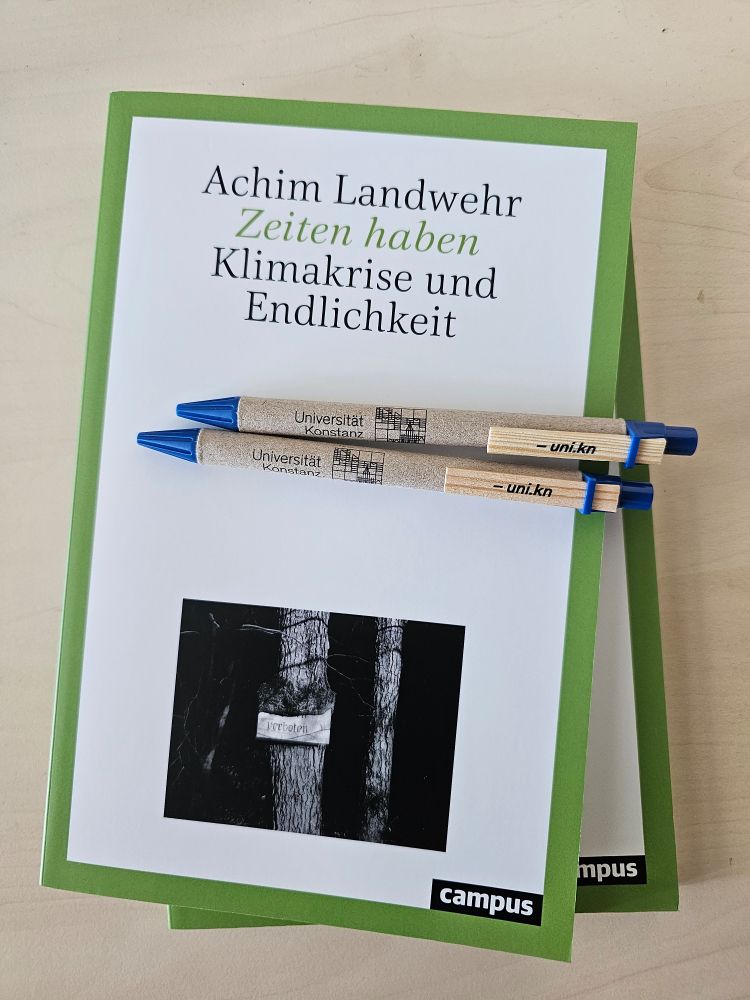 Zwei Exemplare des Buchs "Zeiten haben" und zwei Kulis der Uni Konstanz.