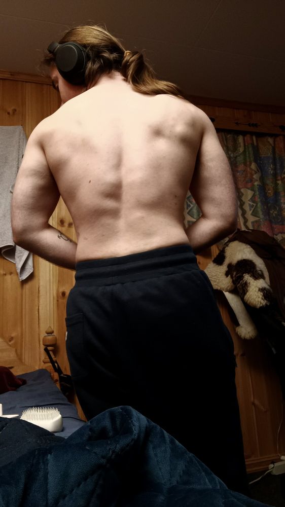 North with his back to the camera, shirtless and with tracksuit pants on.