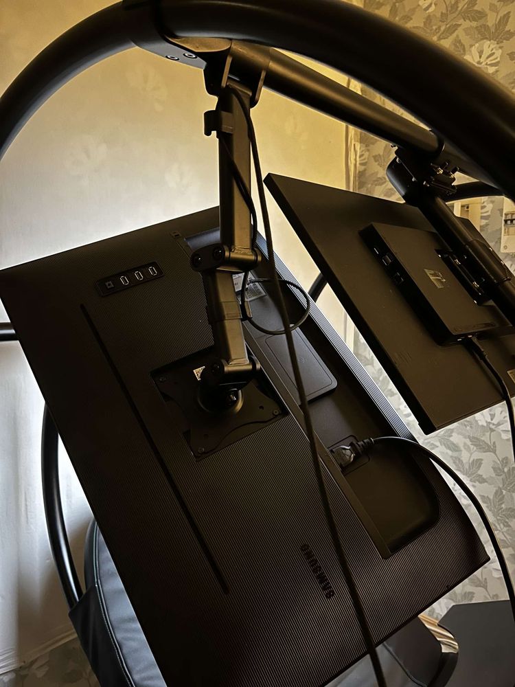 A photo of two monitors suspended from a Levus Zero-Workstation frame. One of the monitors in a vertical position, the other centered and horisontal.