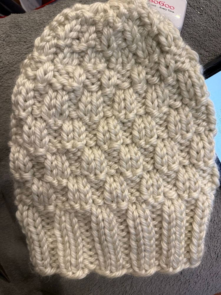 A cream kit hat with a checkerboard detail.
