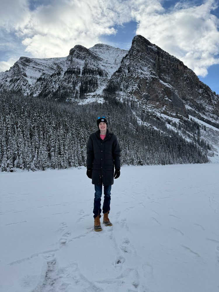Me standing on frozen lake Louise with snowy mountains in the background