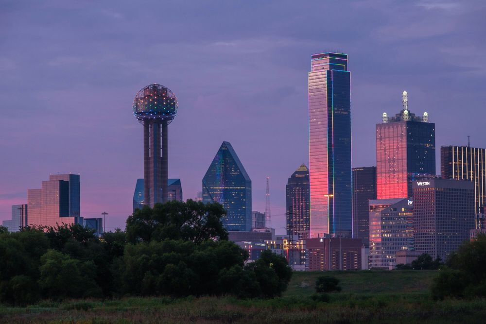 Image of downtown Dallas at dusk with a purple/pink hue.