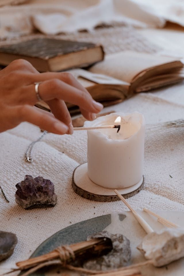 A white candle being lit, showing a small flame.