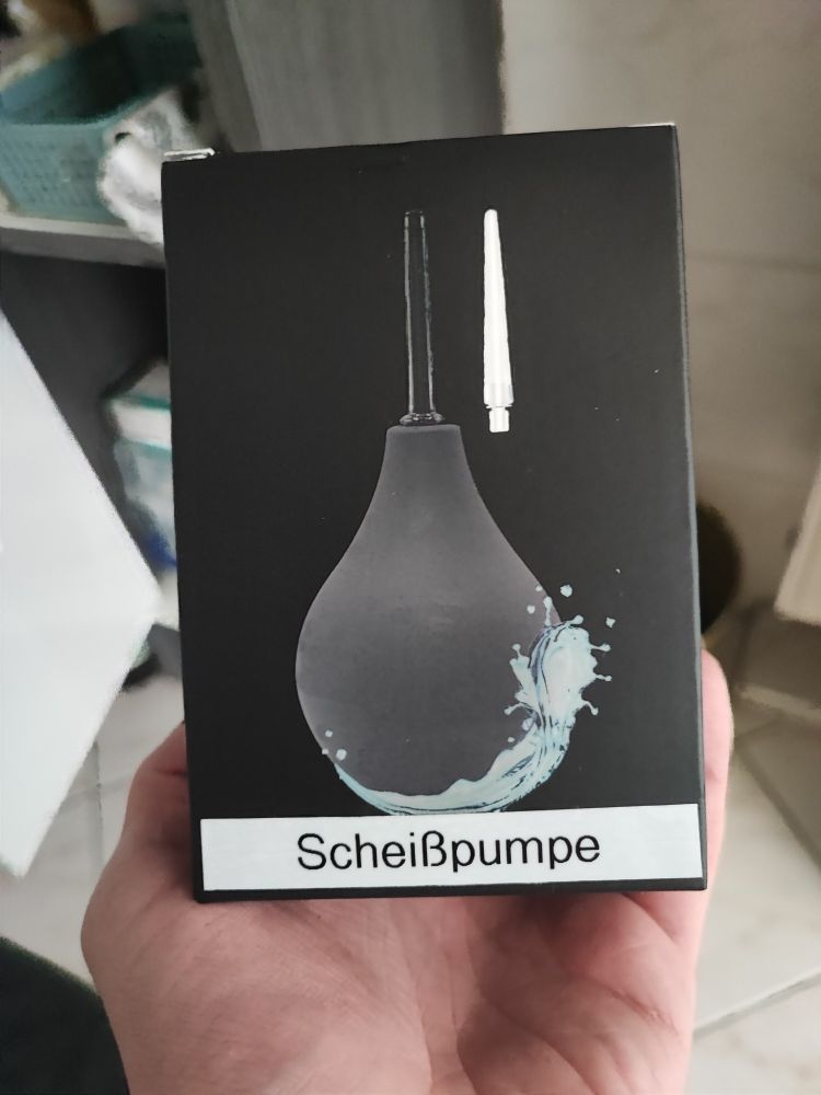 Foto der Verpackung einer Analdusche. Mit einem Etikettiergerät wurde "Scheißpumpe" darauf geschrieben
