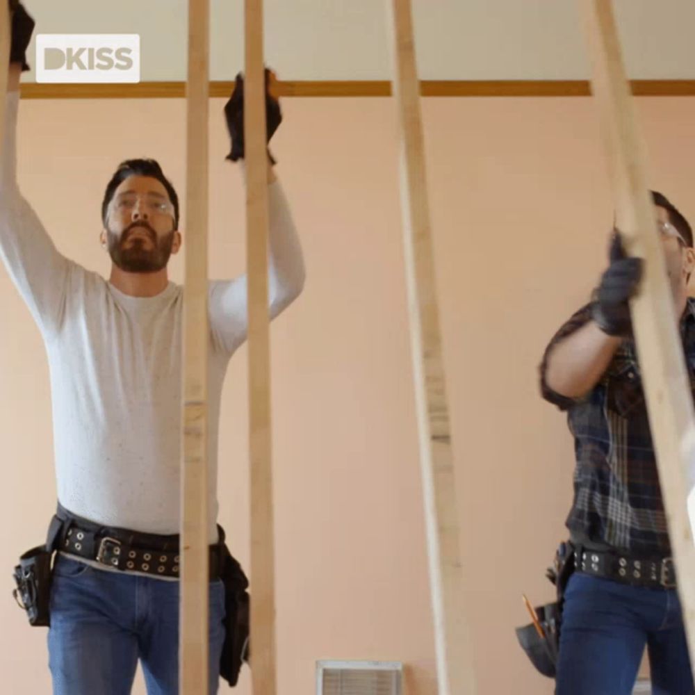 two men are working on a wall with a kiss logo in the corner