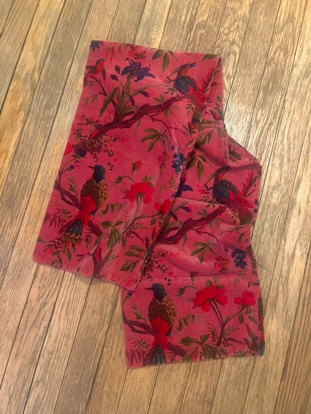 A pink scarf with a bird and flower motif (you know the one) pooled elegantly on a hardwood floor.