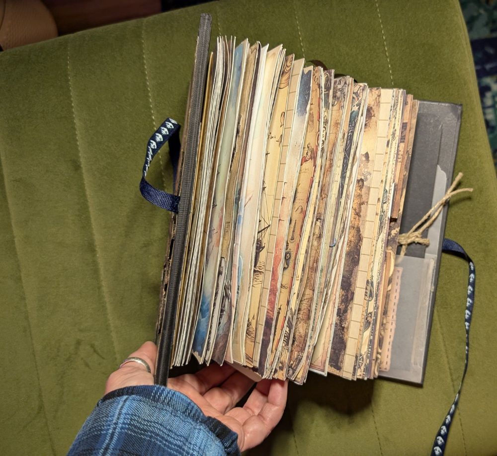 A hand is opening the journal showing off the edges of it's many pages