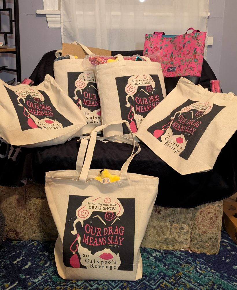  6 tote bags sitting on a chair covered in a black blanket