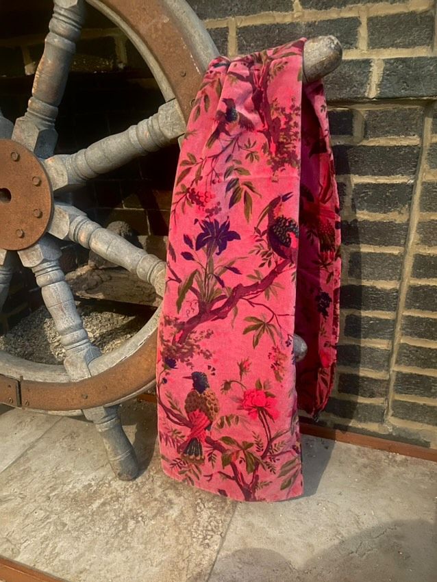 A pink scarf with a bird and flower motif (you know the one) artfully draped over a ship wheel.