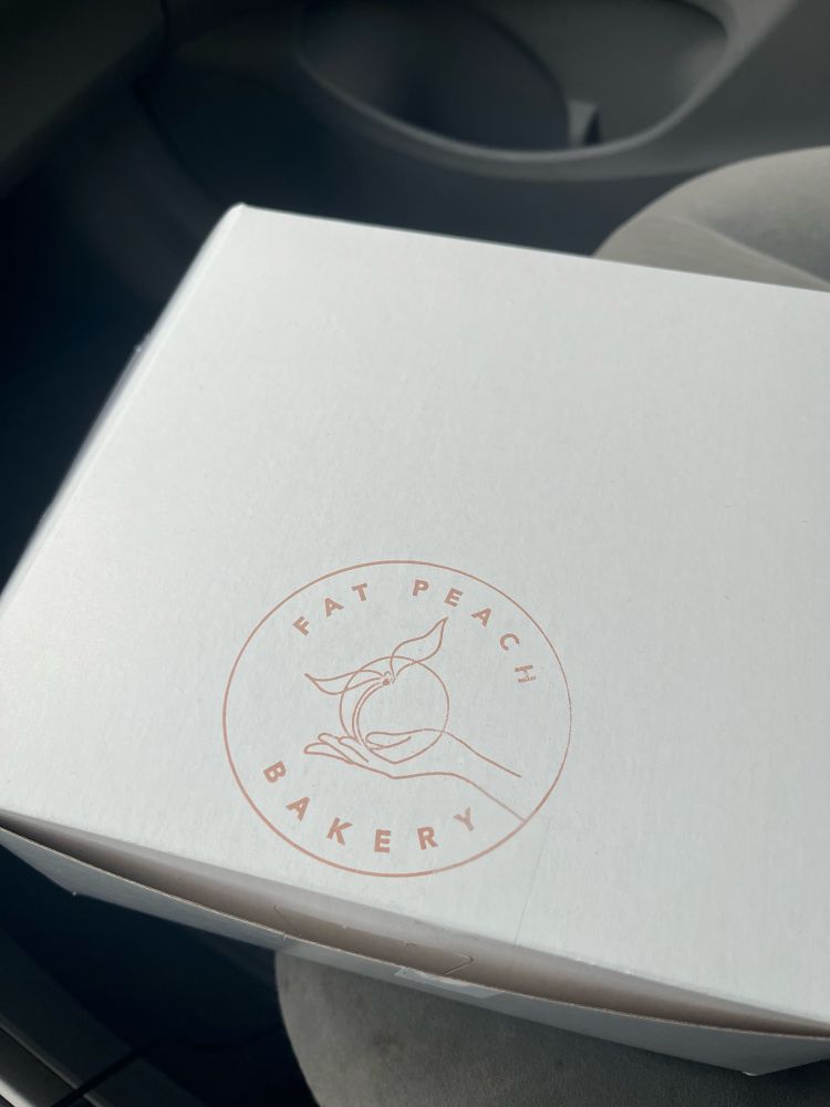 Box of pastries in the front seat of my car with logo saying : Fat Peach Bakery. 