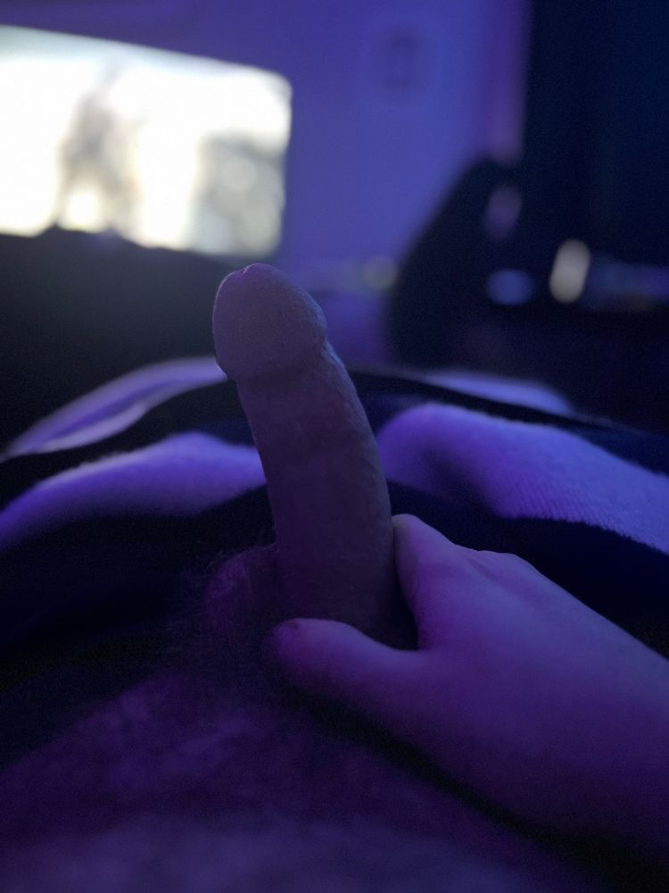 The light casts a purple hue as my hand grips the base of my hard cock in the foreground. 
