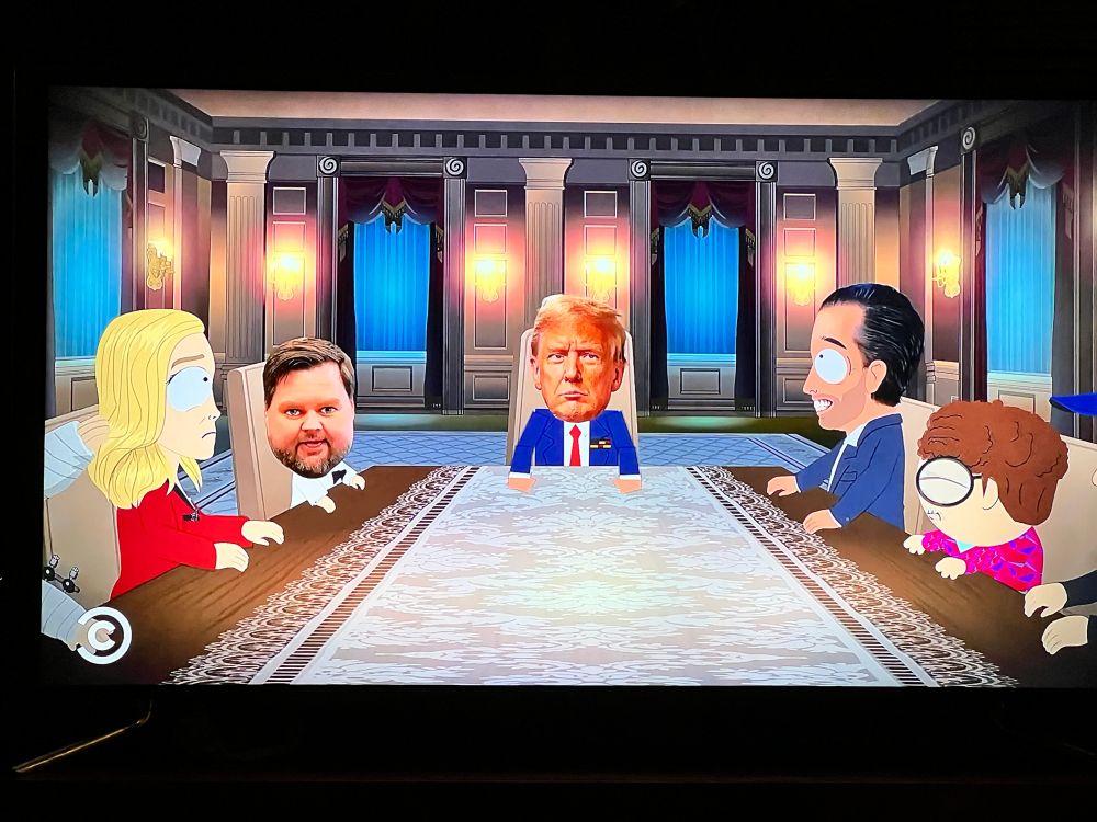 Screenshot of South Park:
Seated around a long table in the WH, left to right: Pam Bondi, JD Vance, Donald Trump at the head of the table, a jumbo/wide-eyed DJT Junior, and a South Park Elementary School student.