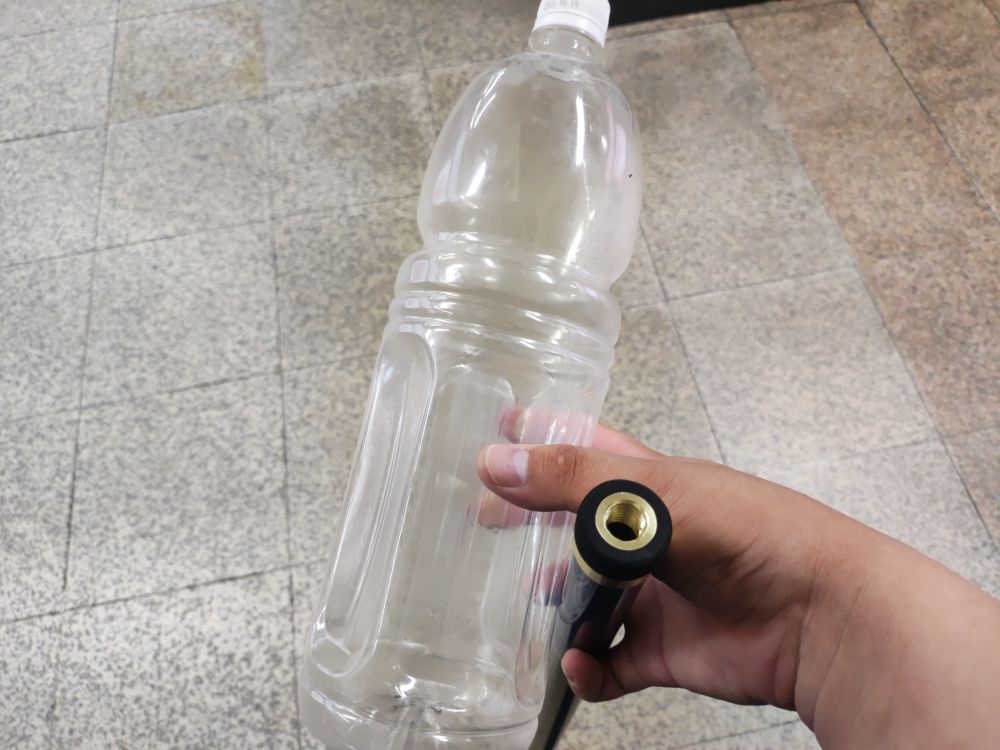 대리석 재질 바닥을 배경으로 깃대용 봉과 빈 1.5리터 들이 페트병을 들고 있는 손.